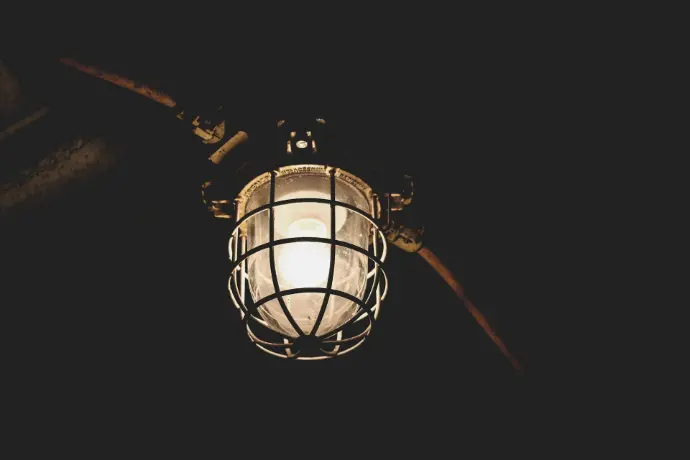 A white light hanging from a ceiling in a dark room